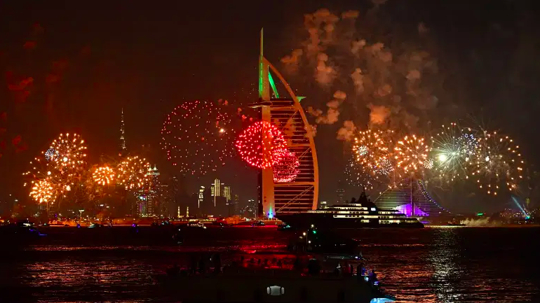 Las celebraciones de fuegos artificiales de Año Nuevo se ven sobre el horizonte de Dubai con el Burj Al Arab (R) y el Burj Khalifa (L), el edificio más alto del mundo, el 31 de diciembre de 2019.