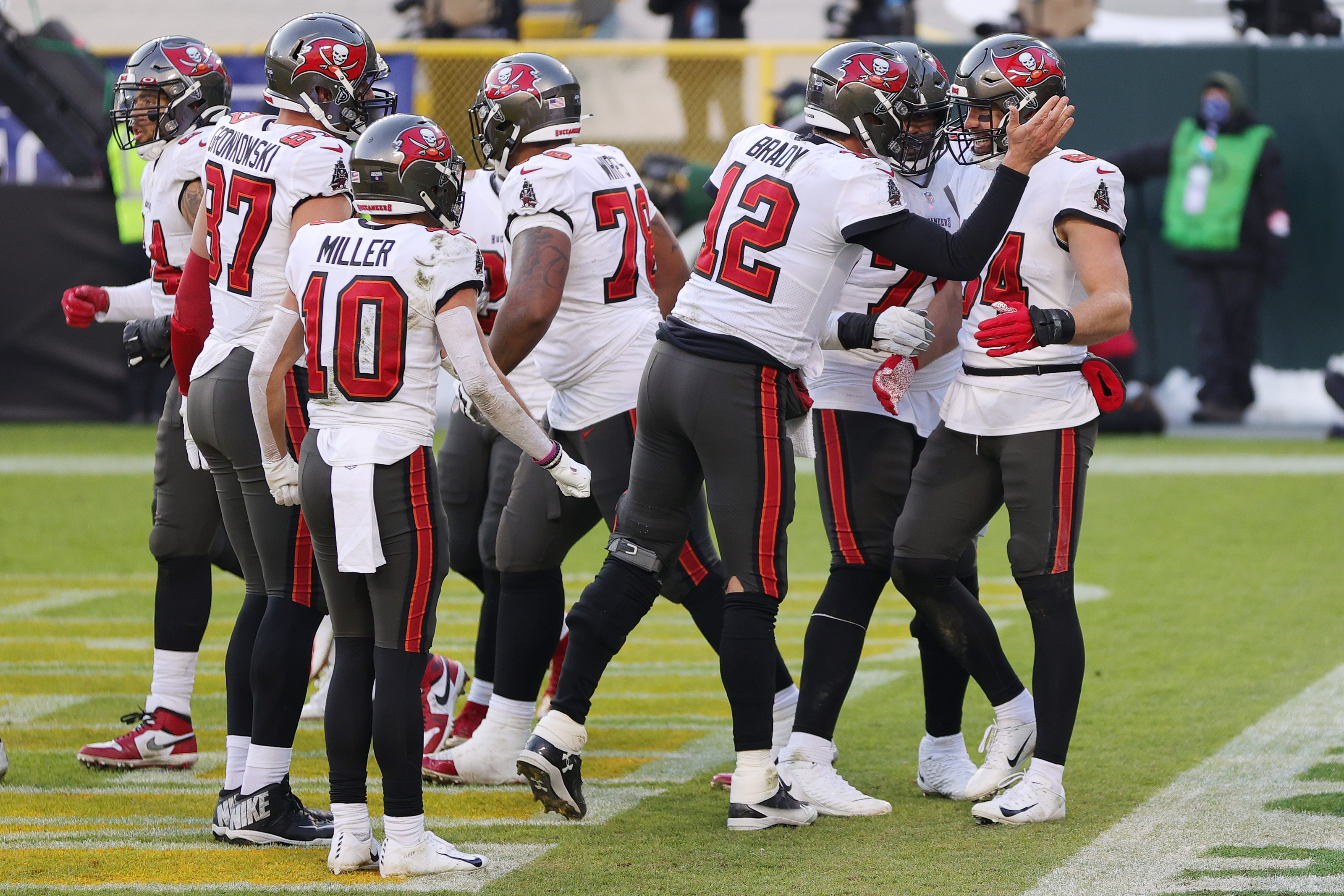 Tom Brady # 12 celebra con Cameron Brate # 84 de los Tampa Bay Buccaneers después de que Brate anotara un touchdown en el tercer cuarto contra los Green Bay Packers durante el juego de campeonato de la NFC en Lambeau Field el 24 de enero de 2021 en Green Bay, Wisconsin.