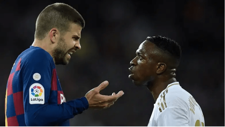 El defensor español del Barcelona Gerard Piqué (L) habla con el delantero brasileño del Real Madrid Vinicius Junior durante el partido de fútbol de la Liga española entre el Real Madrid y el Barcelona en el estadio Santiago Bernabeu en Madrid el 1 de marzo de 2020