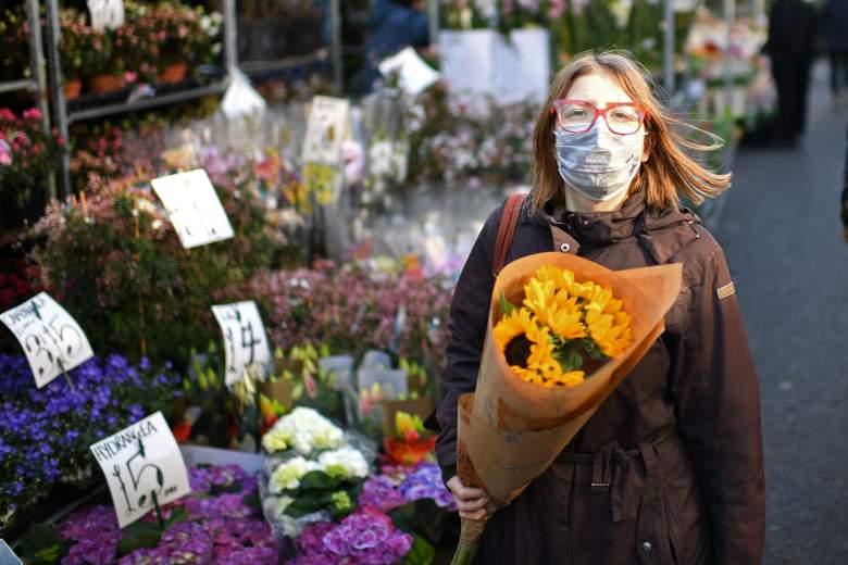 Una mujer que lleva una mascarilla protectora lleva un ramo de flores durante una visita al mercado de flores de Columbia Road en el este de Londres el Día de la Madre, 22 de marzo de 2020.