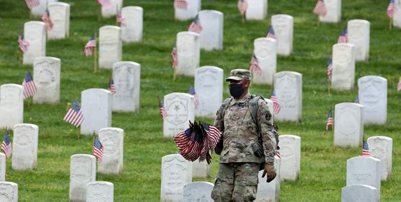 Un soldado del 3er Regimiento de Infantería, o la "Vieja Guardia", trabaja para colocar banderas de Estados Unidos frente a todas las tumbas delante del Memorial Día de fin de semana en el Cementerio Nacional de Arlington el 21 de mayo de 2020 en Arlington, Virginia.