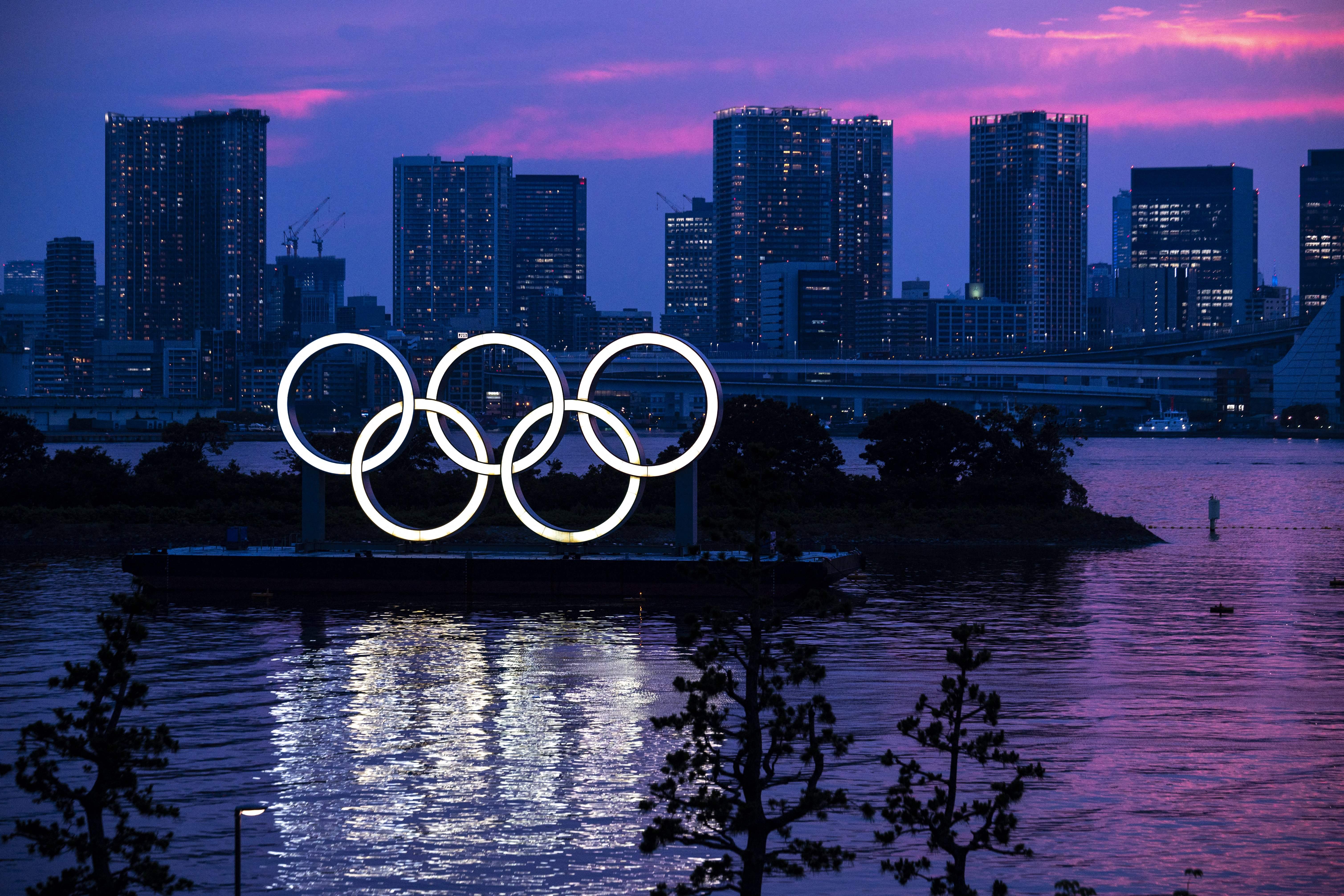 Una vista general muestra los anillos olímpicos iluminados al anochecer en el paseo marítimo de Odaiba en Tokio el 12 de Juky de 2021.