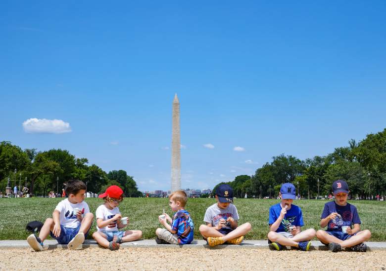 Un grupo de niños se sienta a disfrutar de un helado del camión de helados "America is Back" en el National Mall el 4 de julio de 2021 en Washington, DC.