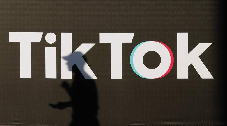 Un joven que sostiene un teléfono inteligente proyecta una sombra mientras pasa junto a un anuncio de la empresa de redes sociales TikTok el 21 de septiembre de 2020 en Berlín, Alemania.