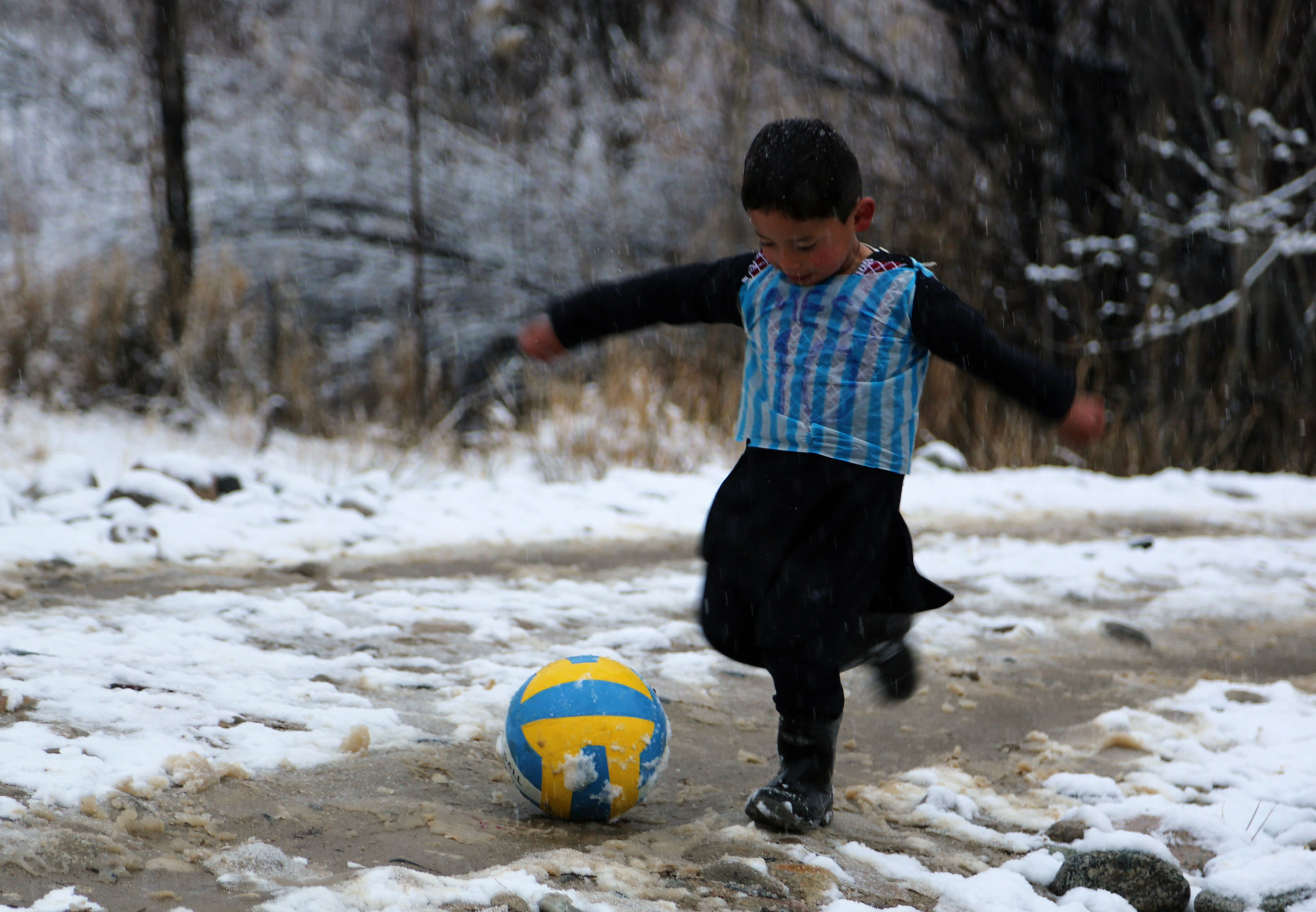 En esta fotografía tomada el 29 de enero de 2016, el niño afgano y fanático de Lionel Messi, Murtaza Ahmadi, de 5 años, usa una camiseta de bolsa de plástico mientras juega al fútbol en el distrito de Jaghori de la provincia de Ghazni.