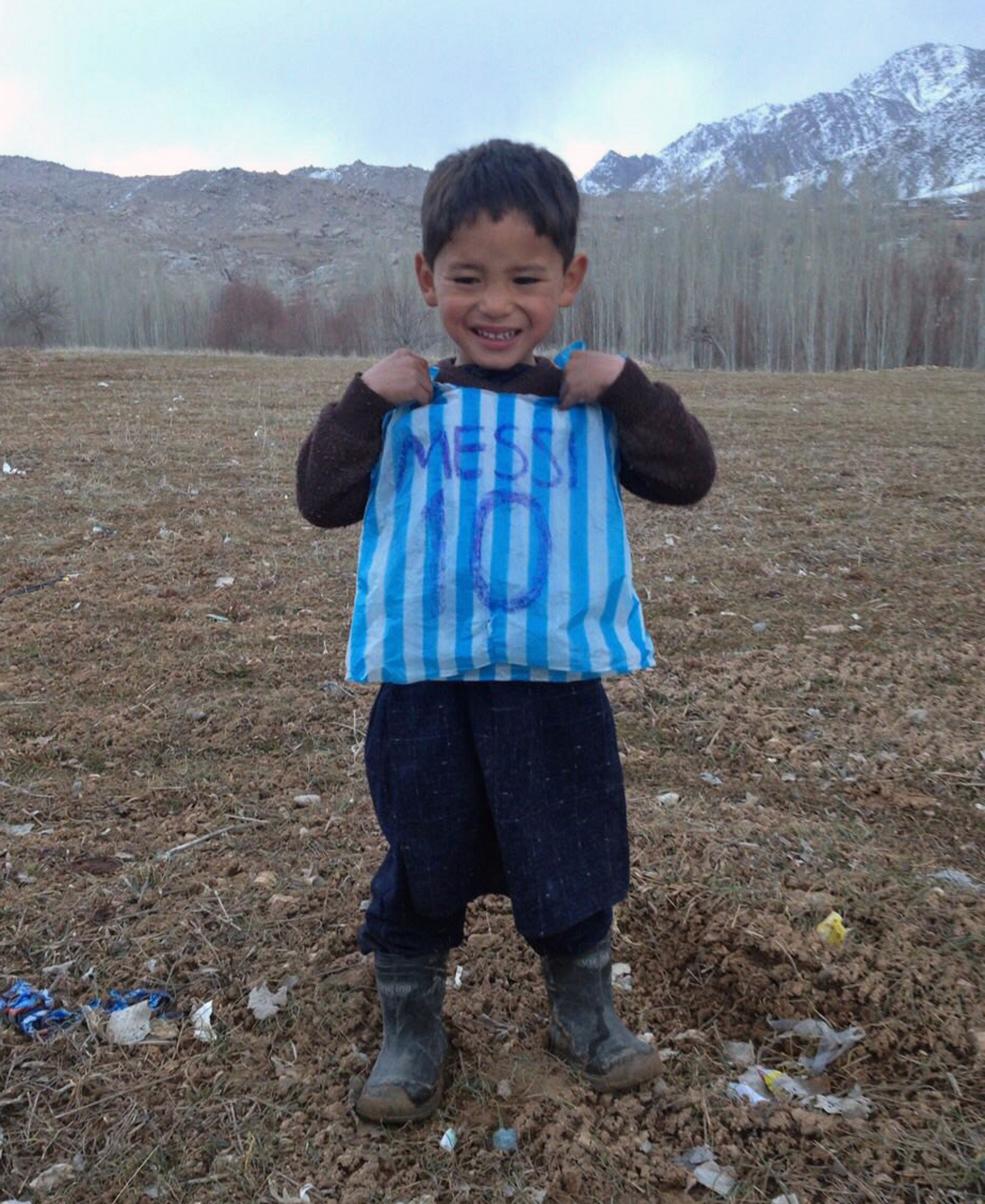 Esta fotografía tomada el 24 de enero de 2016 y proporcionada por la familia del niño afgano y fanático de Lionel Messi Murtaza Ahmadi, de 5 años, con su camiseta de bolsa de plástico en el distrito de Jaghori de la provincia de Ghazni.