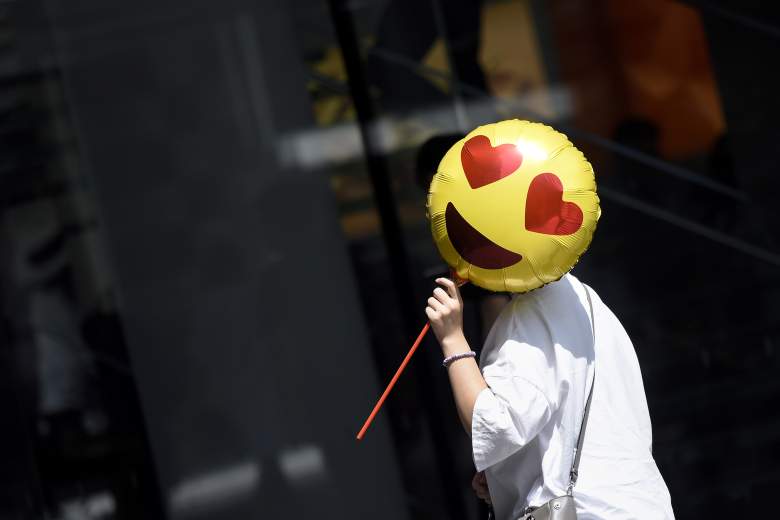 Una mujer sostiene un globo mientras pasa frente a una tienda en el Día de San Valentín chino en Beijing el 28 de agosto de 2017.