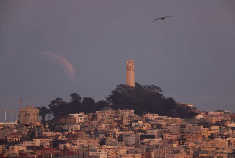 Una luna de sangre parcialmente eclipsada se eleva sobre la Torre Coit de San Francisco el 15 de mayo de 2022 en Sausalito, California.