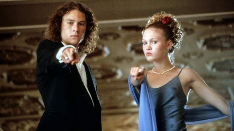 Heath Ledger y Julia Stiles, vestidos de gala, señalan una cámara.
